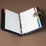 Open weekly planner with colorful tabs on a brown background, symbolizing organization and planning for business growth.