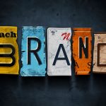 Colorful torn paper letters spelling "BRAND" on dark background, illustrating branding and marketing concepts.