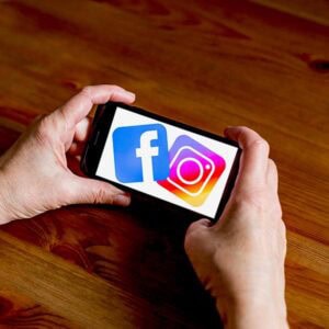 Hands holding phone displaying Facebook and Instagram logos