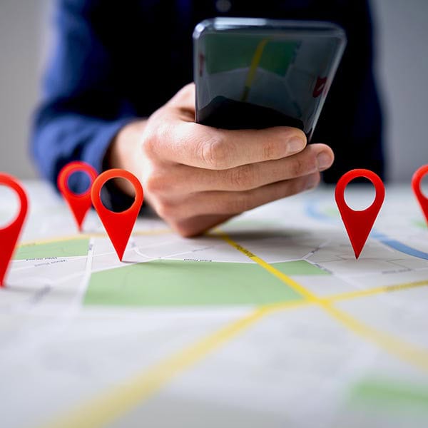 Map With Red Location Marker And Mobile Phone Person using smartphone to navigate map with location pins