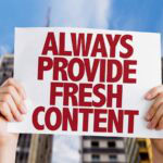 Hands holding sign promoting fresh content creation