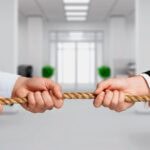 Business people pulling rope in office competition